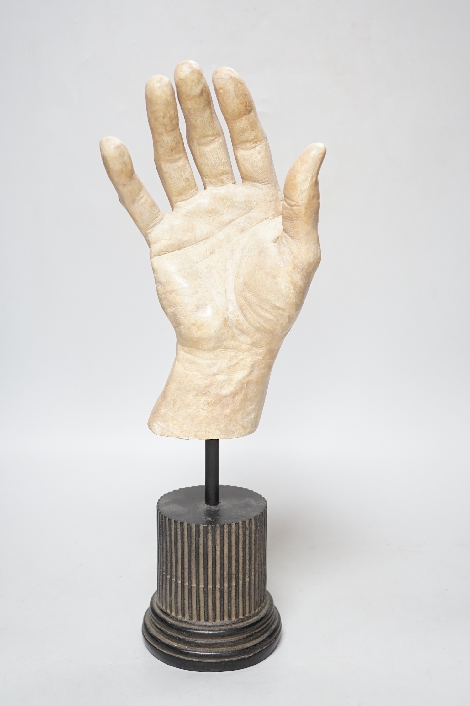 A composition model of a hand raised on a circular column base, 38cm high